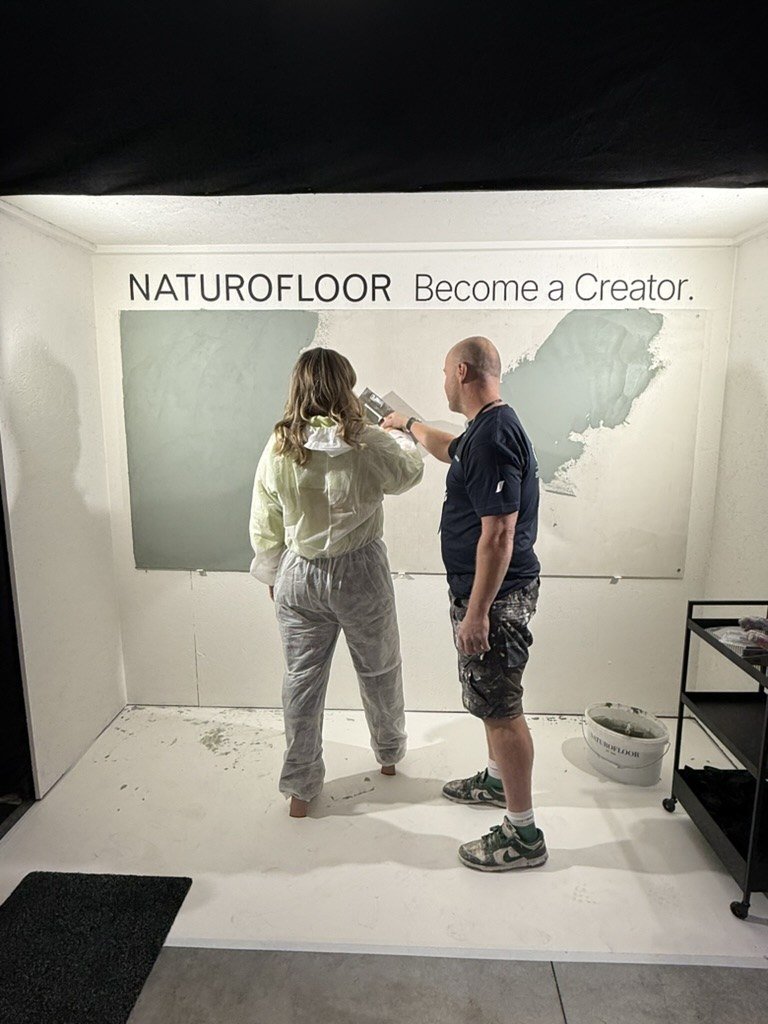 A guest in a protective suit applying the finish in the Become a Creator studio