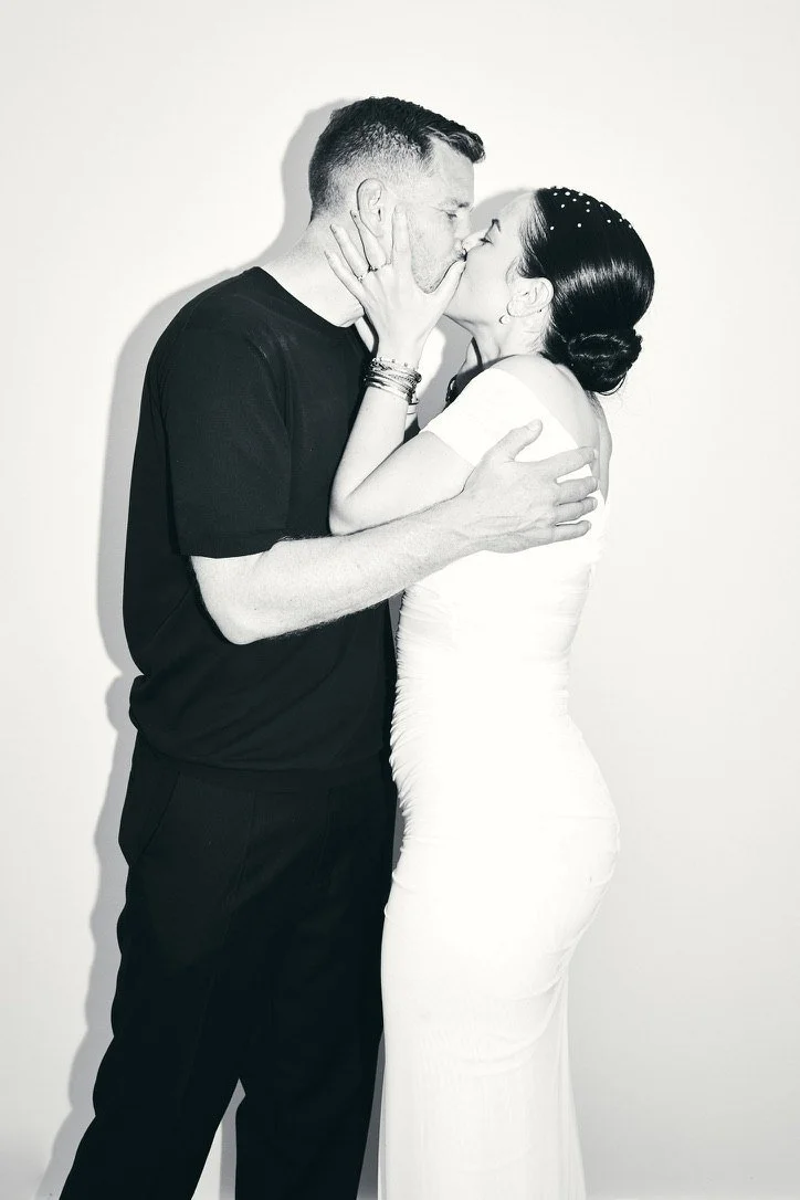 Black-and-white: the couple kissing against a white wall