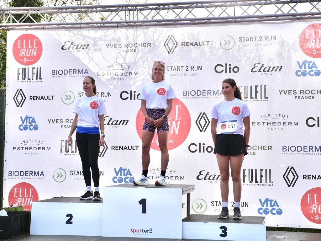 The top three on the podium in front of the partner wall