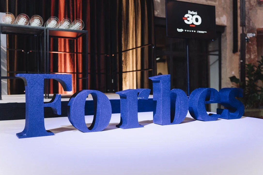 Large blue Forbes letters on stage in front of the 30 Under 30 awards