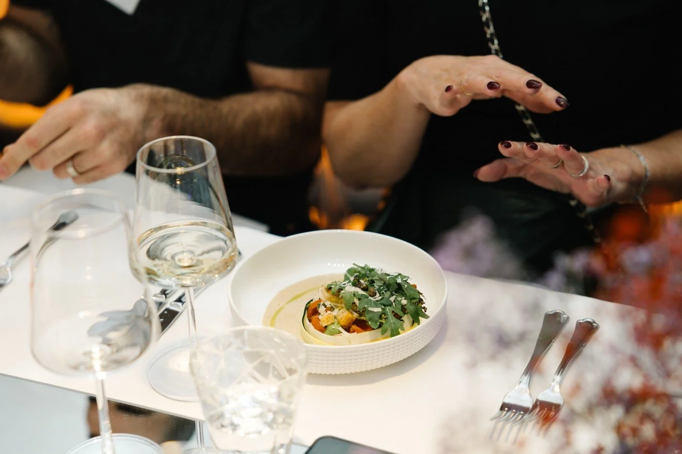 A plated dish and white wine on a white table