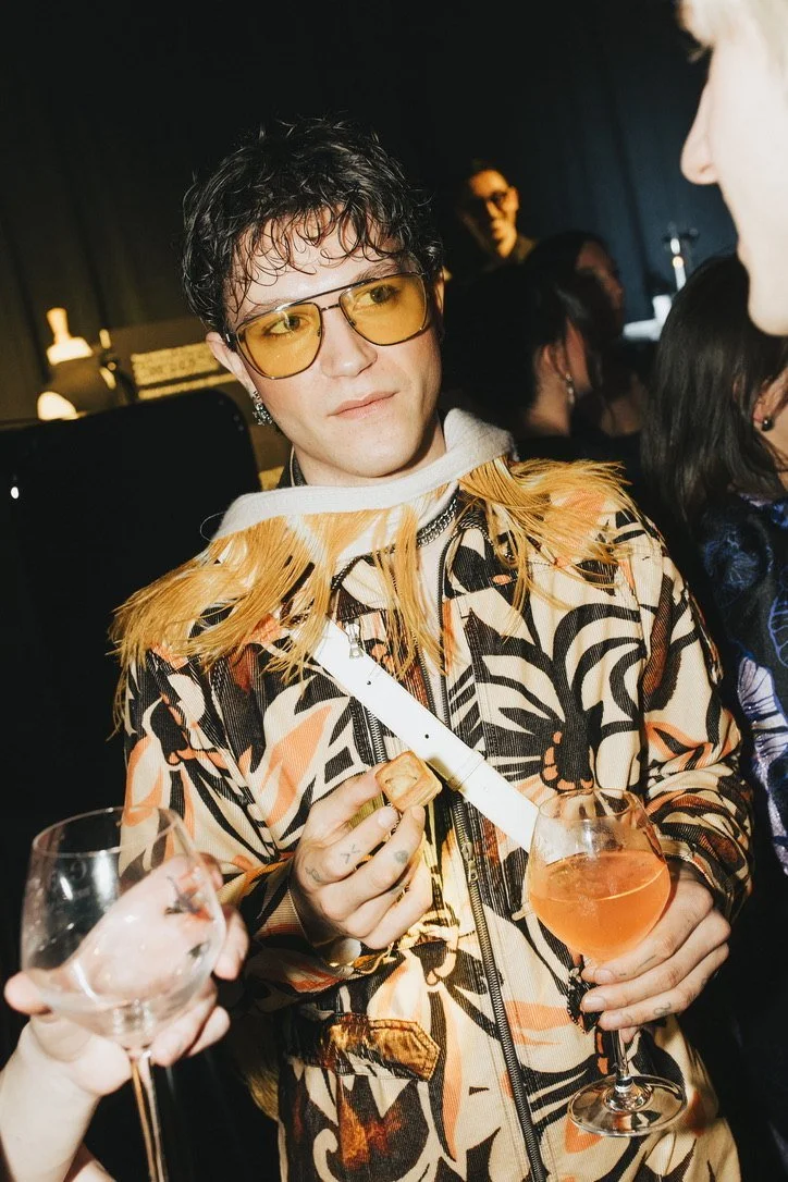 A guest in a fringed jacket with a spritz