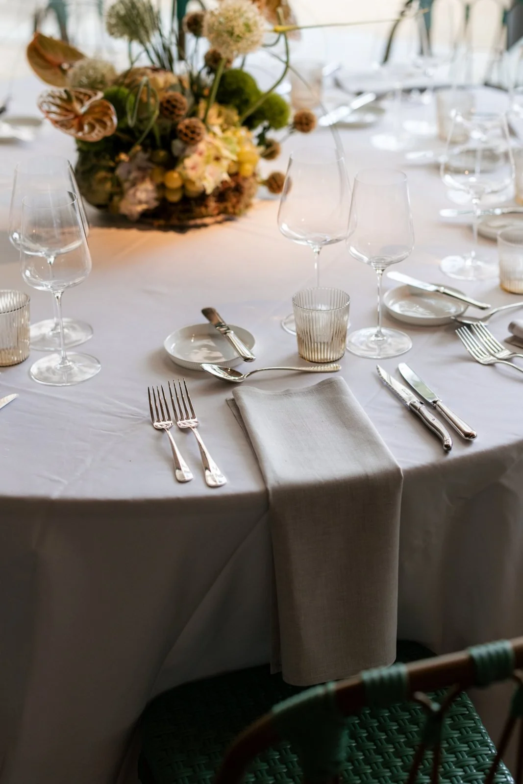 A place setting with crystal glasses and a sculptural flower arrangement