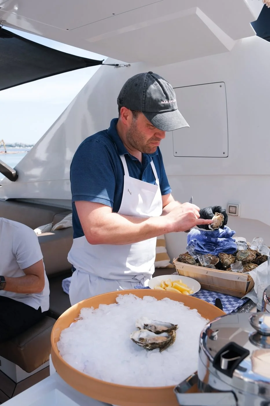 A chef opening oysters on ice on board