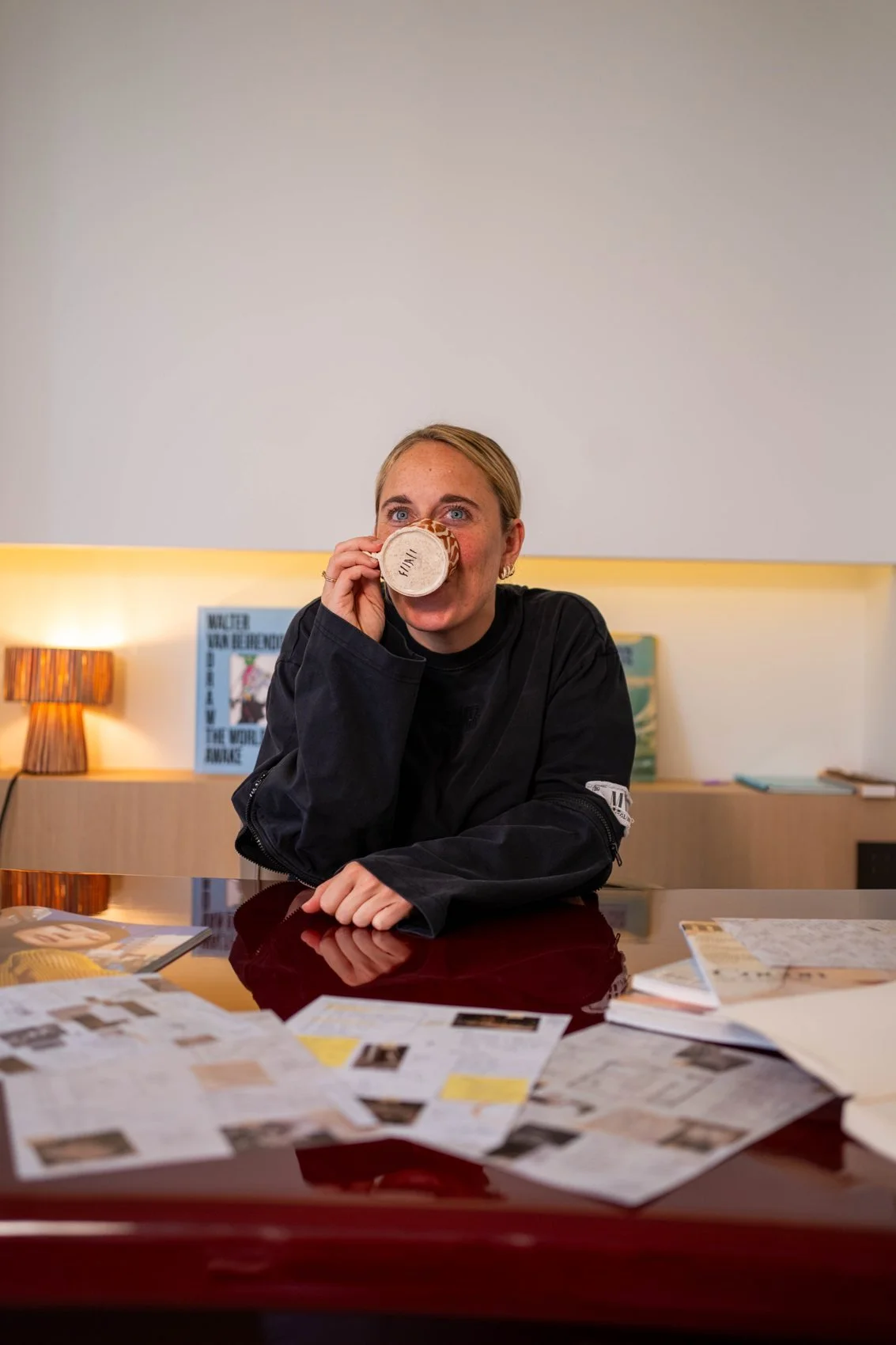 Emily with a coffee at her studio desk, planning between layouts and magazines