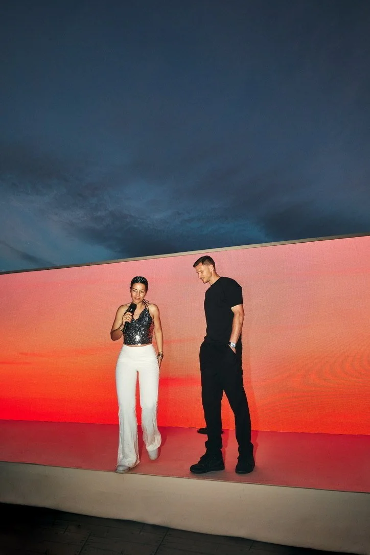 Still from the wedding film of Jan & Sophie: the couple on stage in front of a glowing orange screen