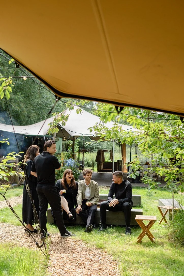 Guests talking on garden benches beside the tent