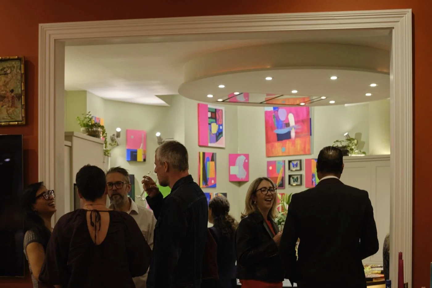 Guests seen through a doorway, with paintings on the walls beyond