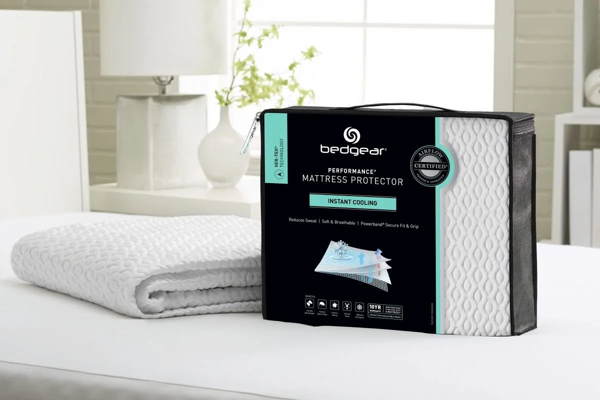 Bedgear Ver-Tex Performance Mattress Protector in its black package with a green Instant Cooling band, beside the folded protector on a bed