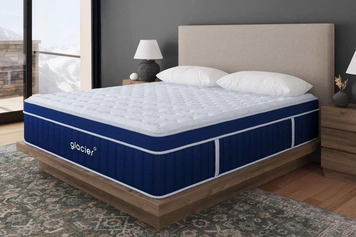 Glacier Sleep mattress with white pillows on a wooden platform bed in a bedroom with a mountain-view window