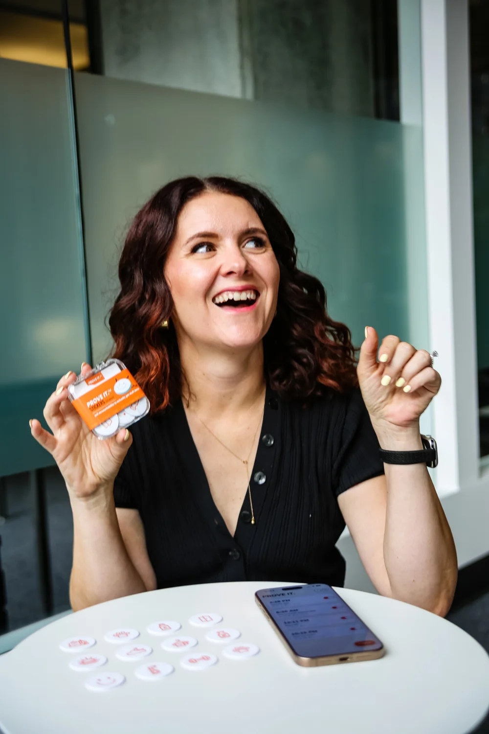 Sharon holding a PROVE IT sticker pack, laughing