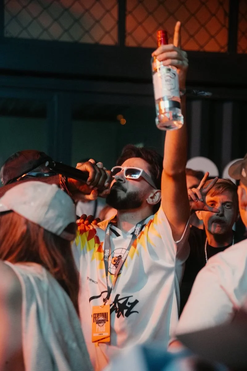 Gast feiert mit erhobener Flasche in der Crowd