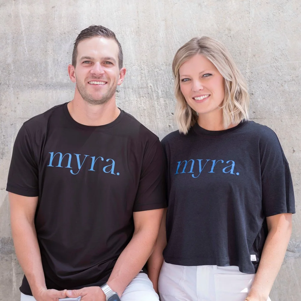 Two team members photographed against a concrete wall outdoors.
