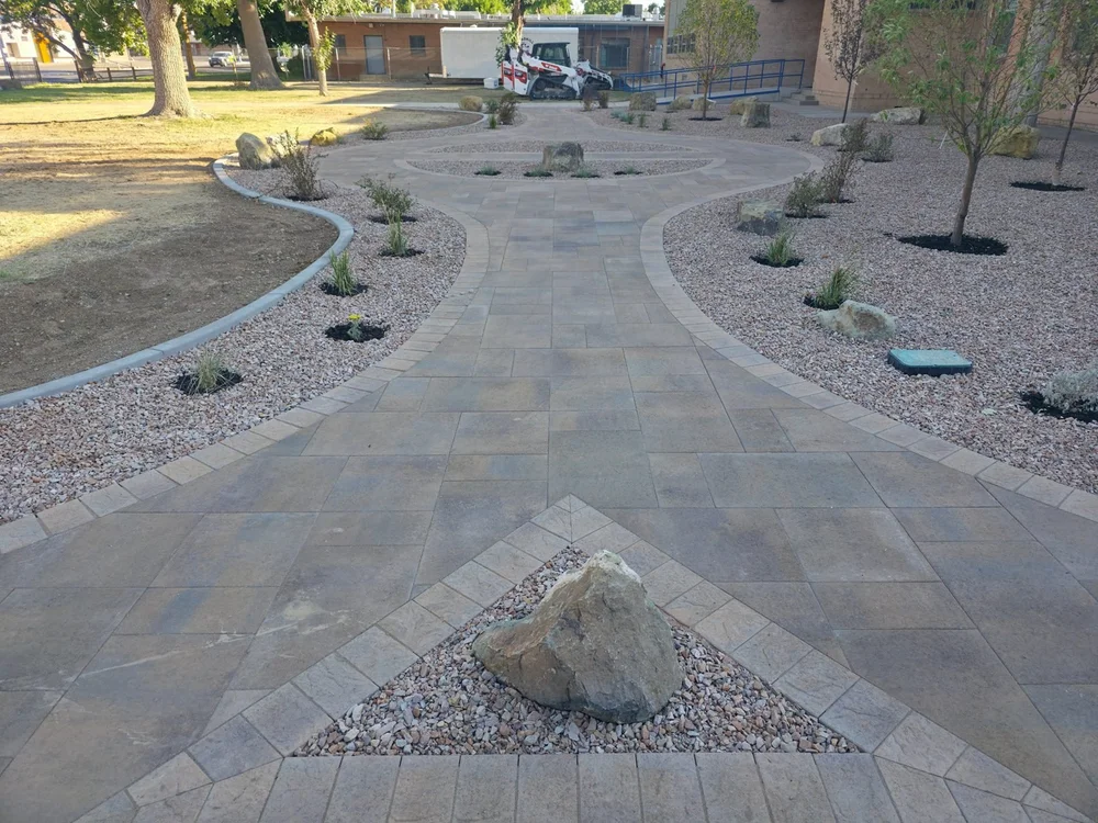 A paver walkway with a boulder set in a triangle inlay