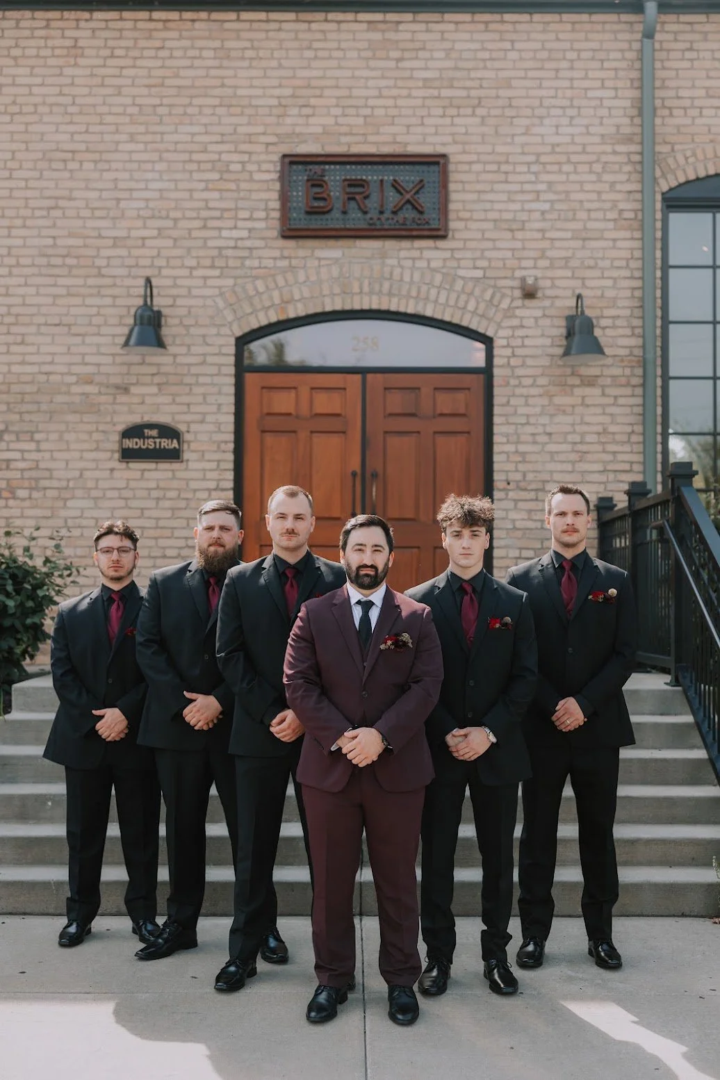 Groom and groomsmen wearing burgundy floral pocket squares and boutonnières