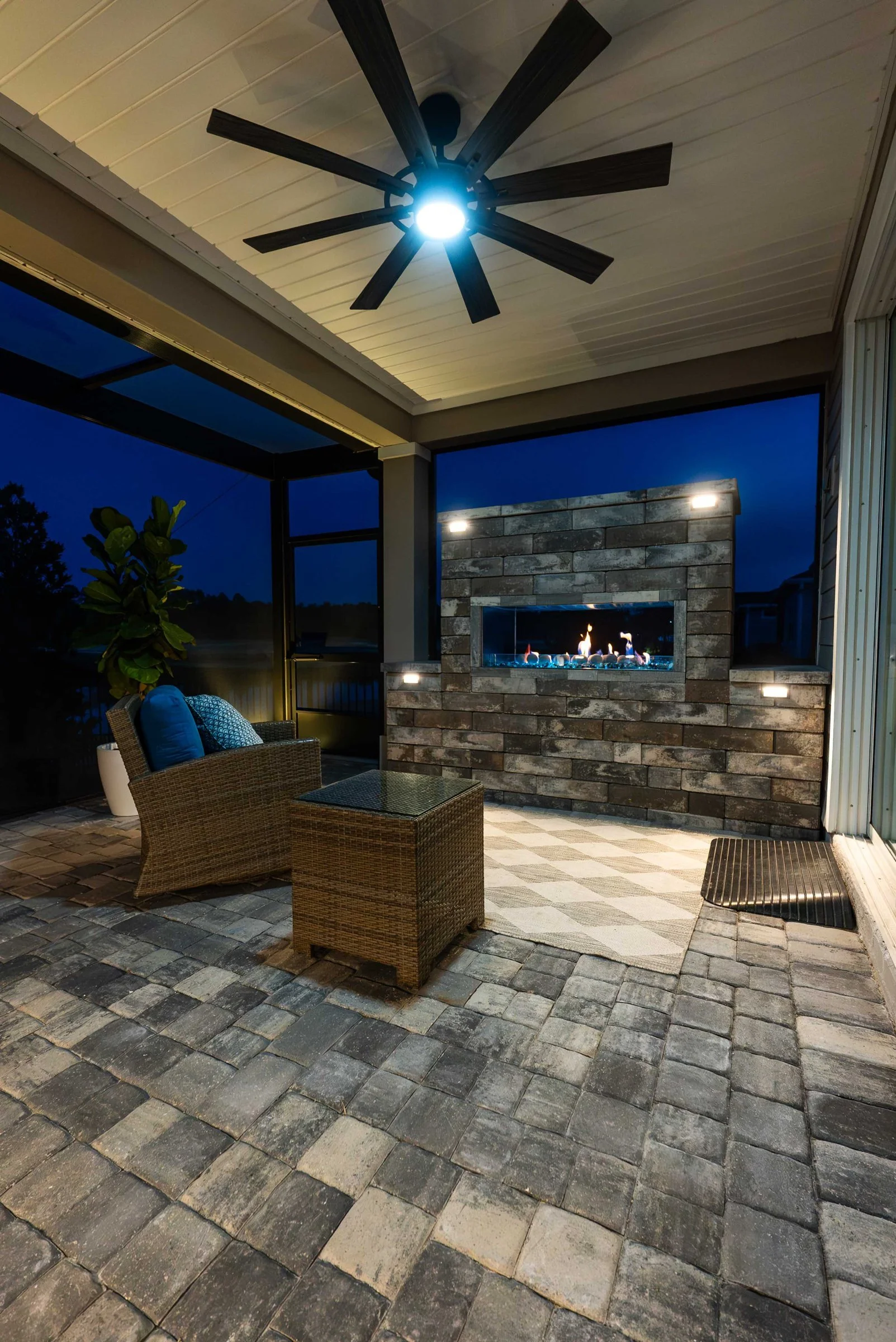 Screened patio with a fireplace and ceiling fan at night in Stillwater, St. Johns