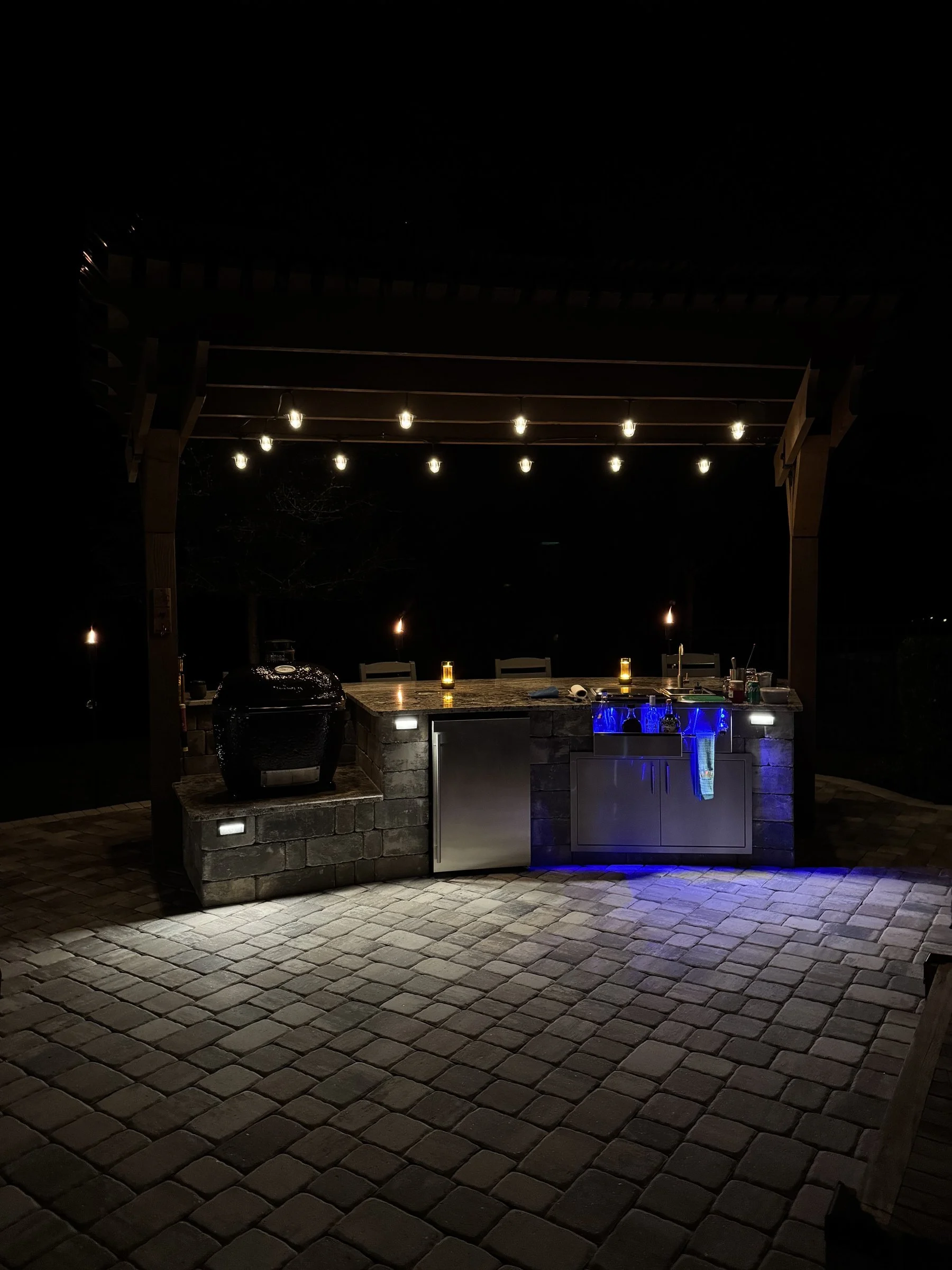 Outdoor kitchen and cedar pergola lit at night in Nocatee