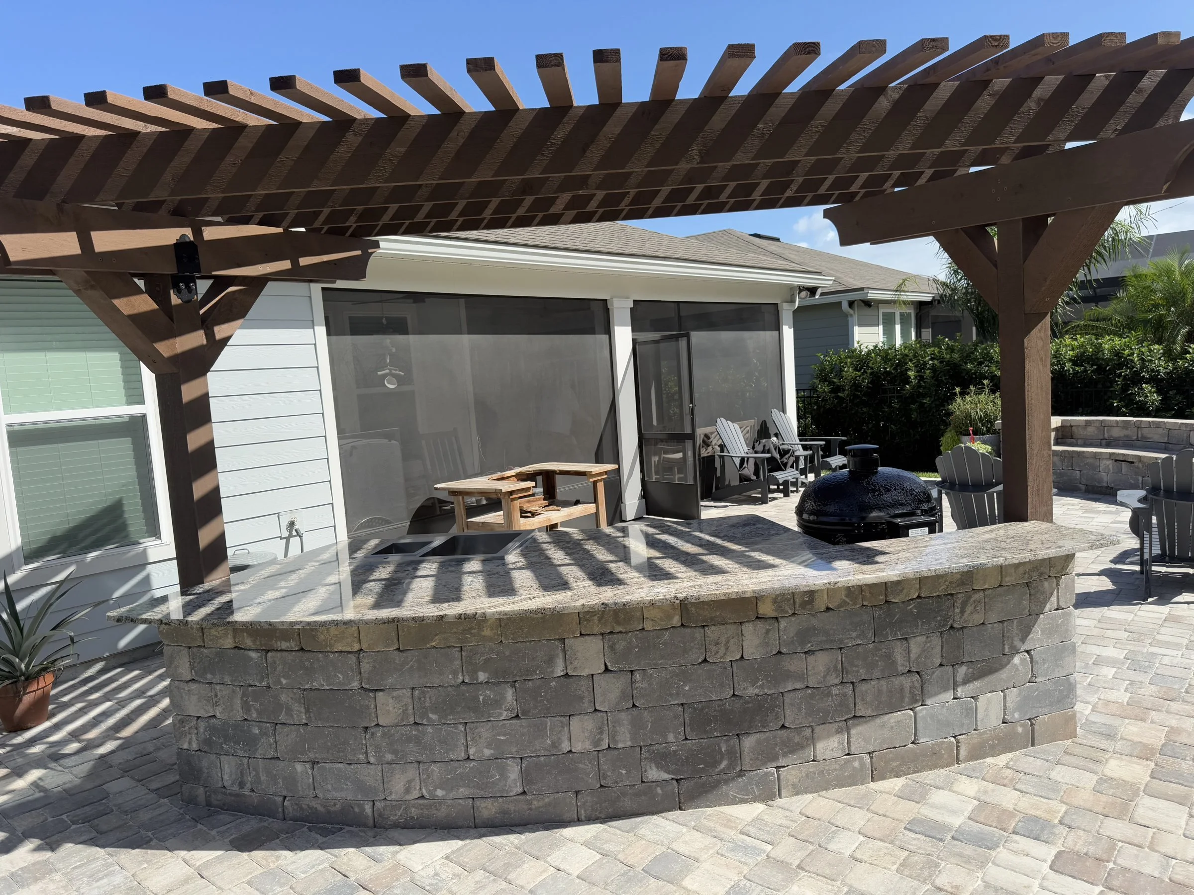 Curved outdoor kitchen under a cedar pergola in Nocatee