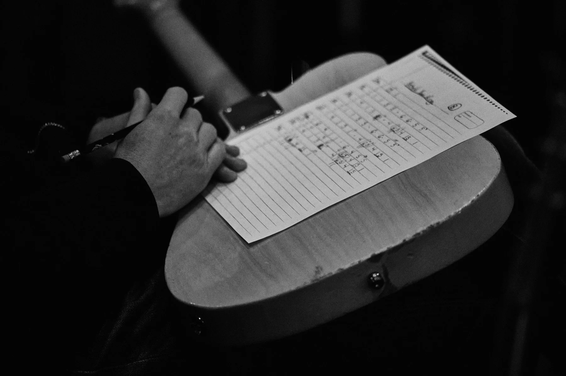 A musician making handwritten notes on a song chart