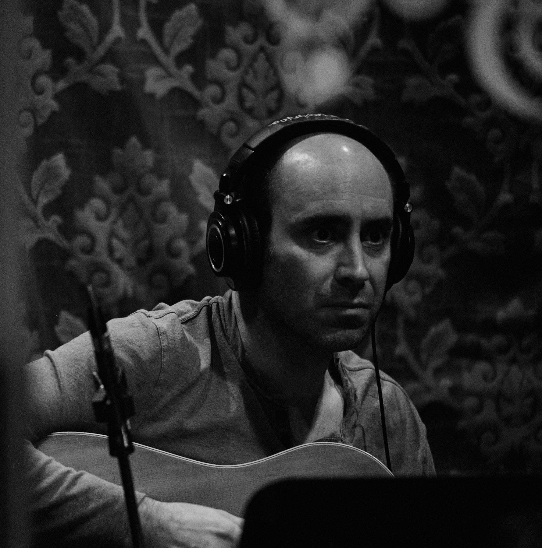 A guitarist wearing headphones during a recording session