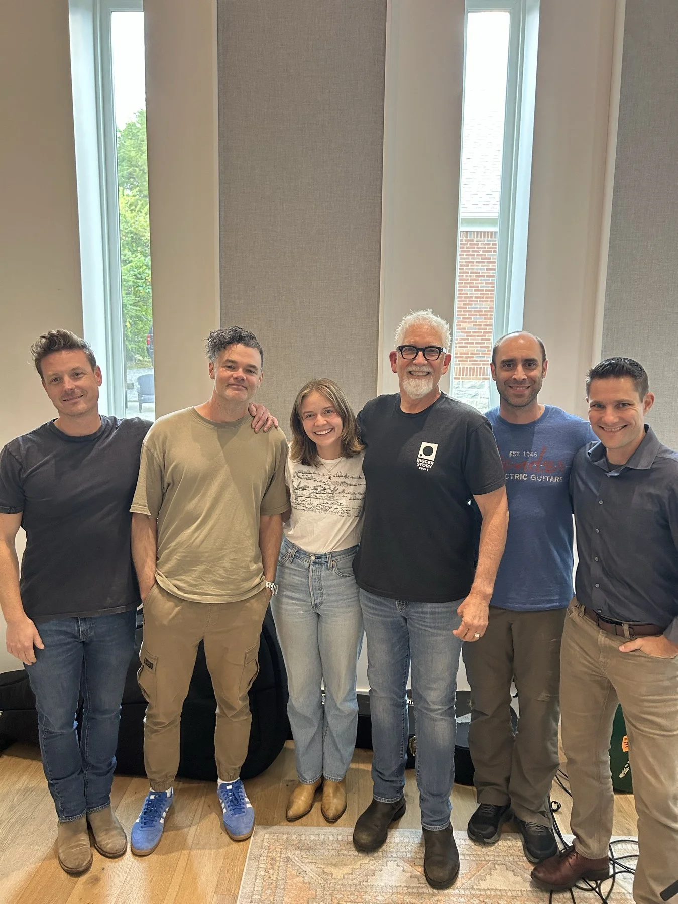 An artist and recording musicians standing together in the studio