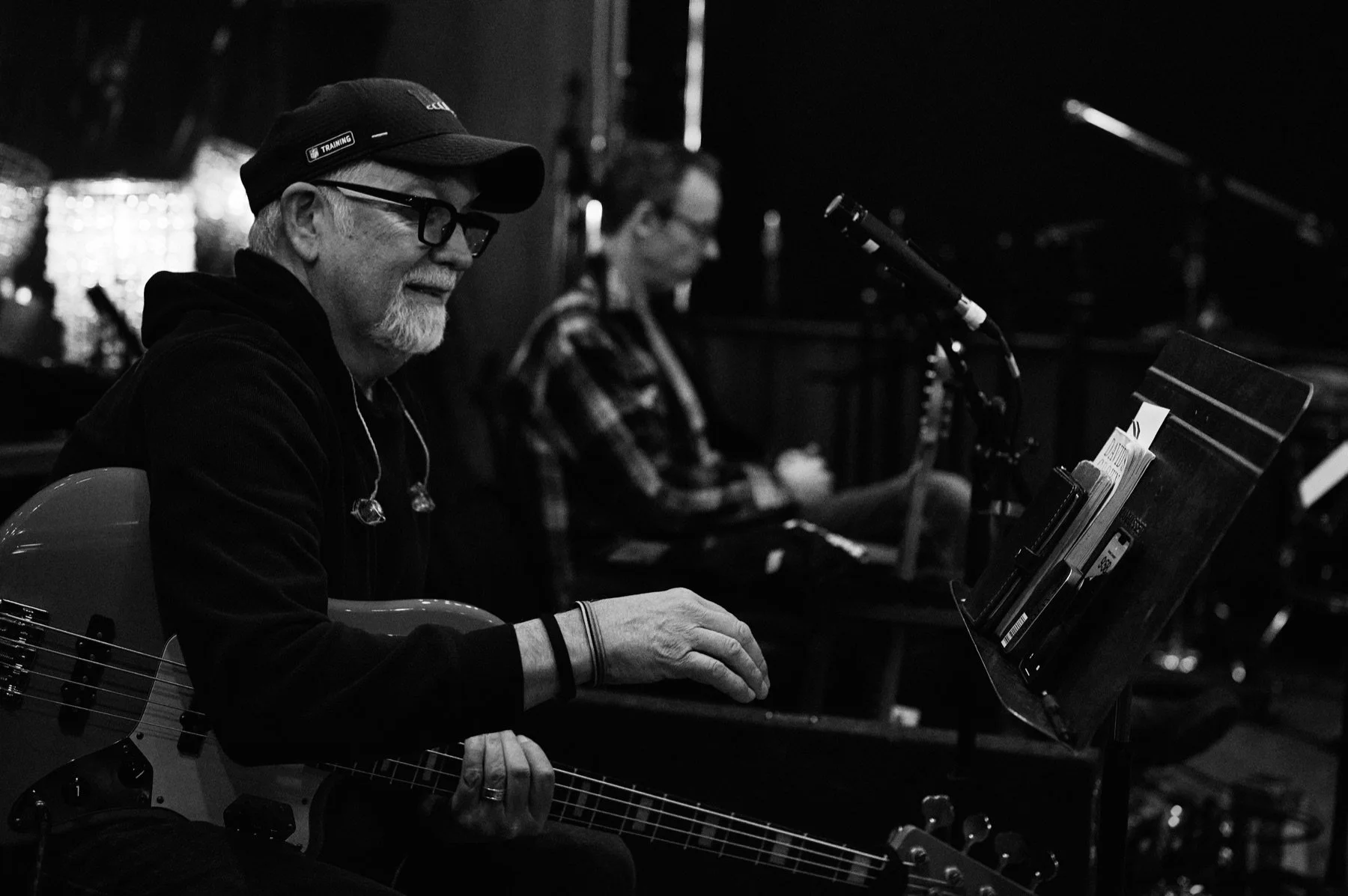 A musician at the studio console with other players in the room