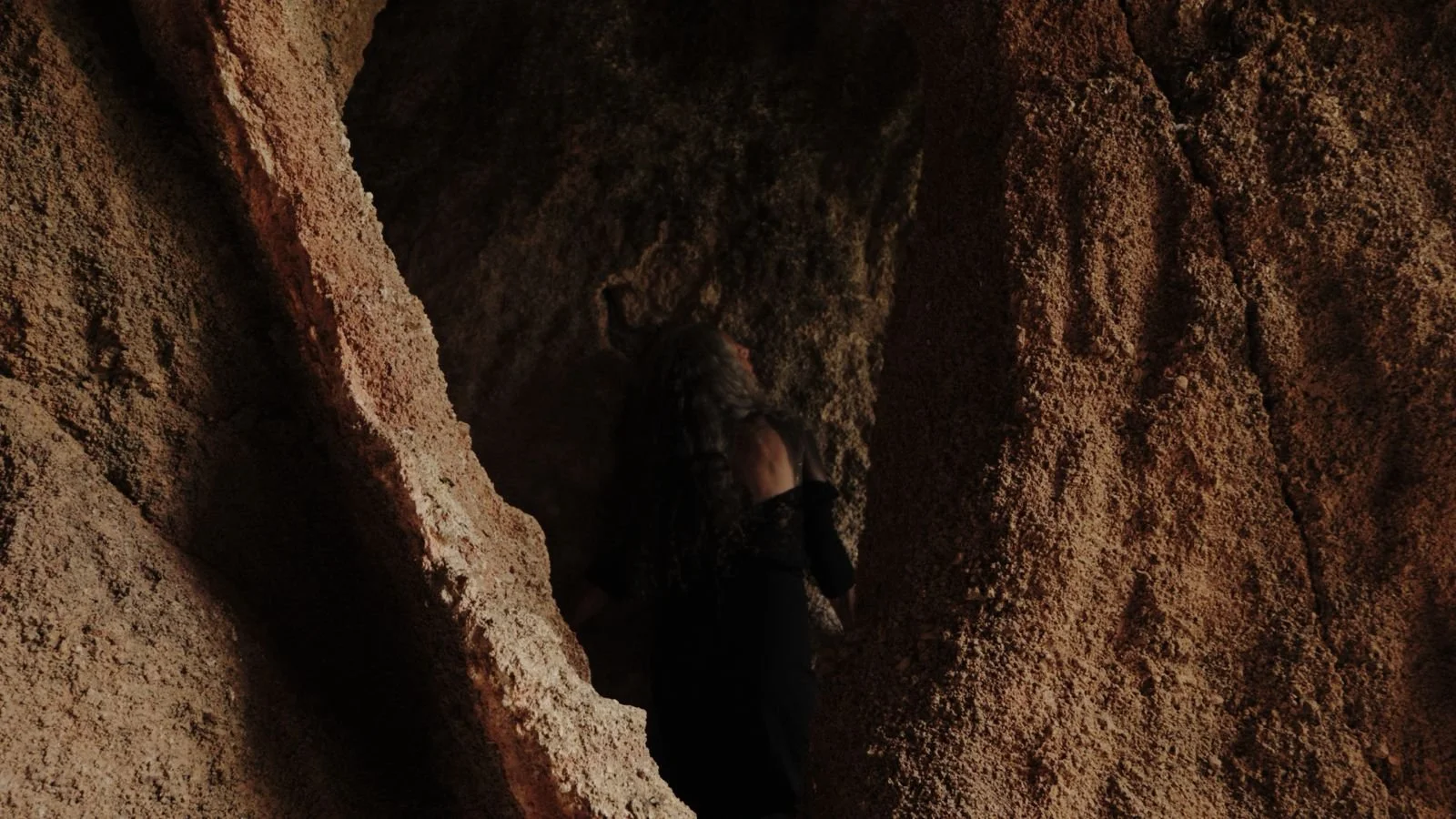 A figure framed by weathered rock formations in MISSING FACE