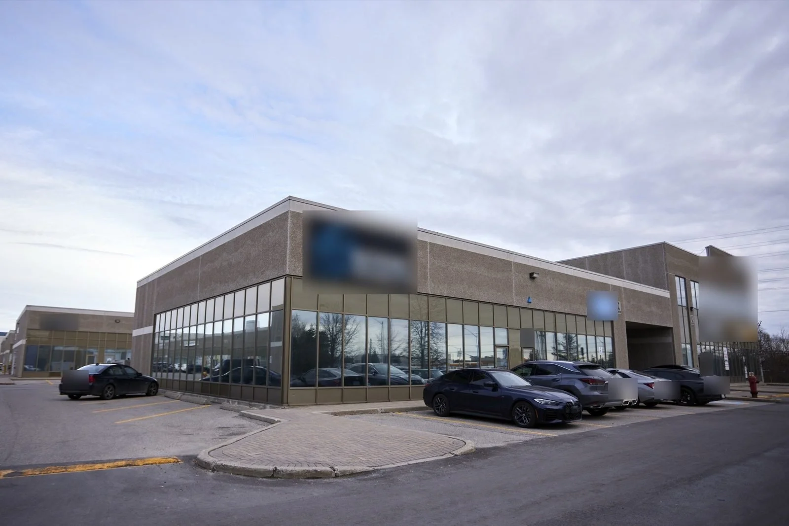 Before, March 2024: the building corner with the previous tenant's sign. Signs and car plates are blurred.