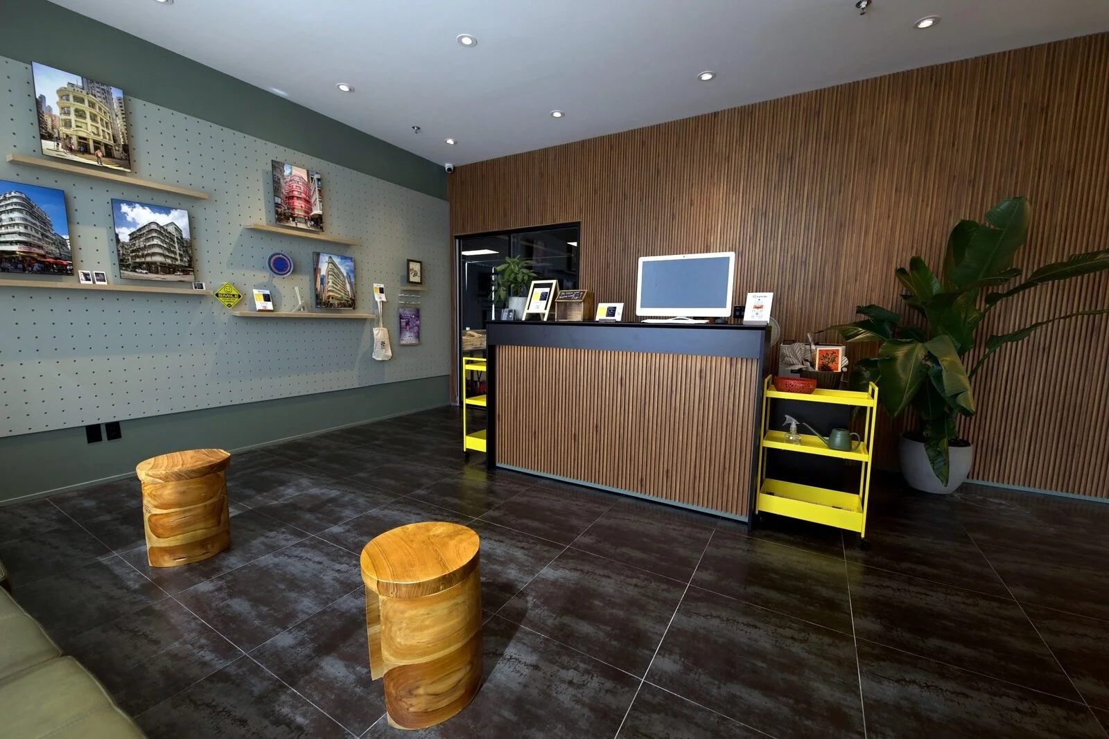 After, August 2024: the new reception with a wood slat counter, a pegboard wall and wood stools. Same counter position; this photo is turned to the right.