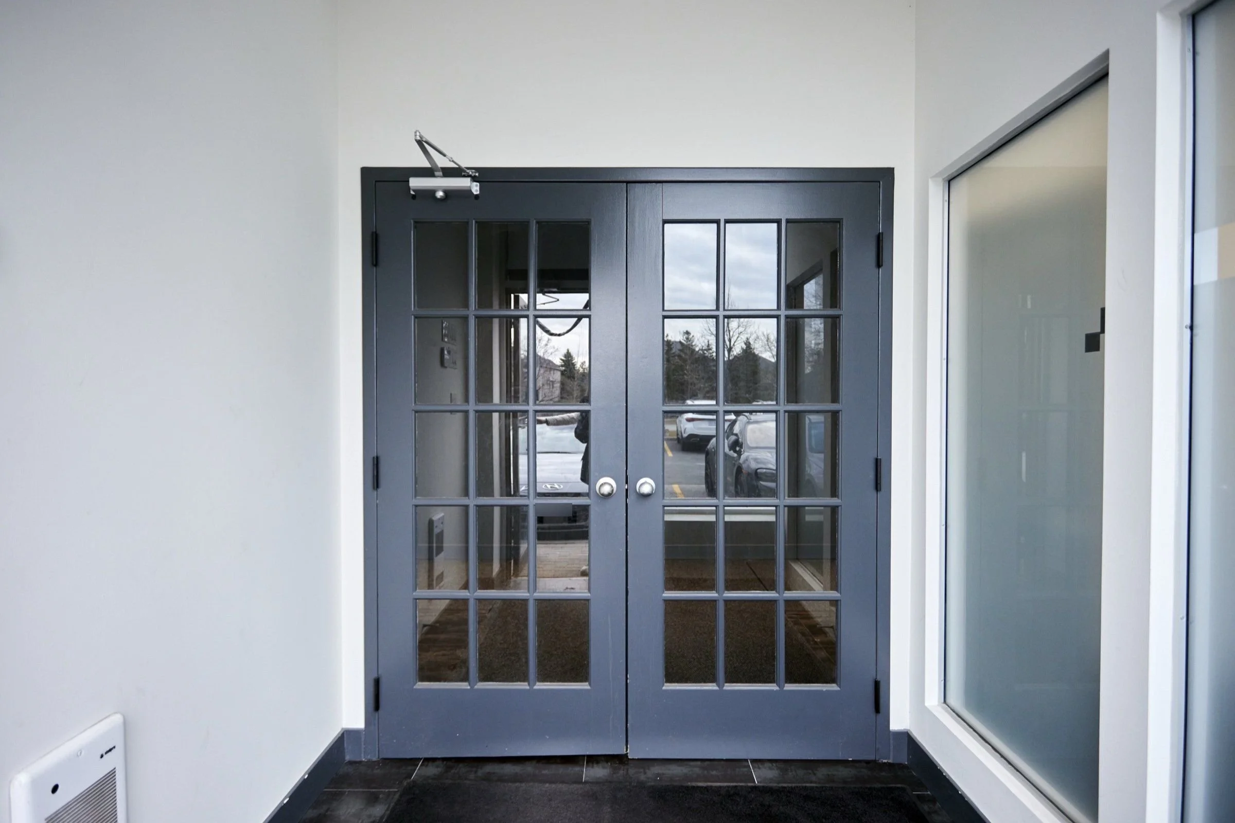 Before, March 2024: the grey double doors at the entrance of the empty unit.