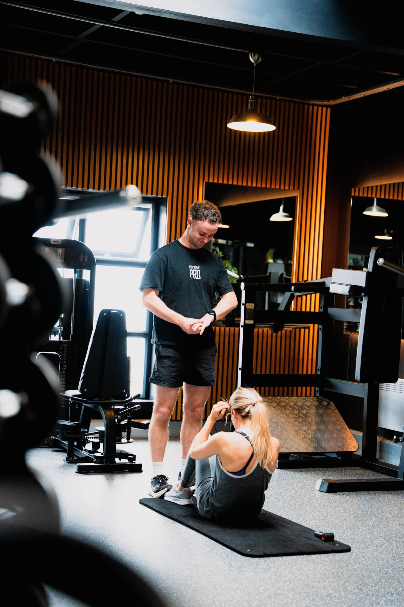 A Physique Pro coach talking with a member on the gym floor at Gosforth