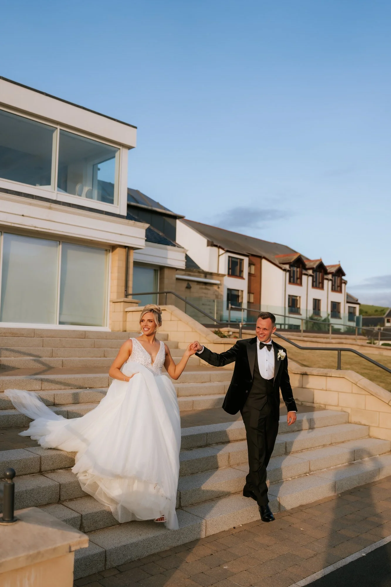 Nicole and Lawrence walking down the hotel steps in warm evening light.