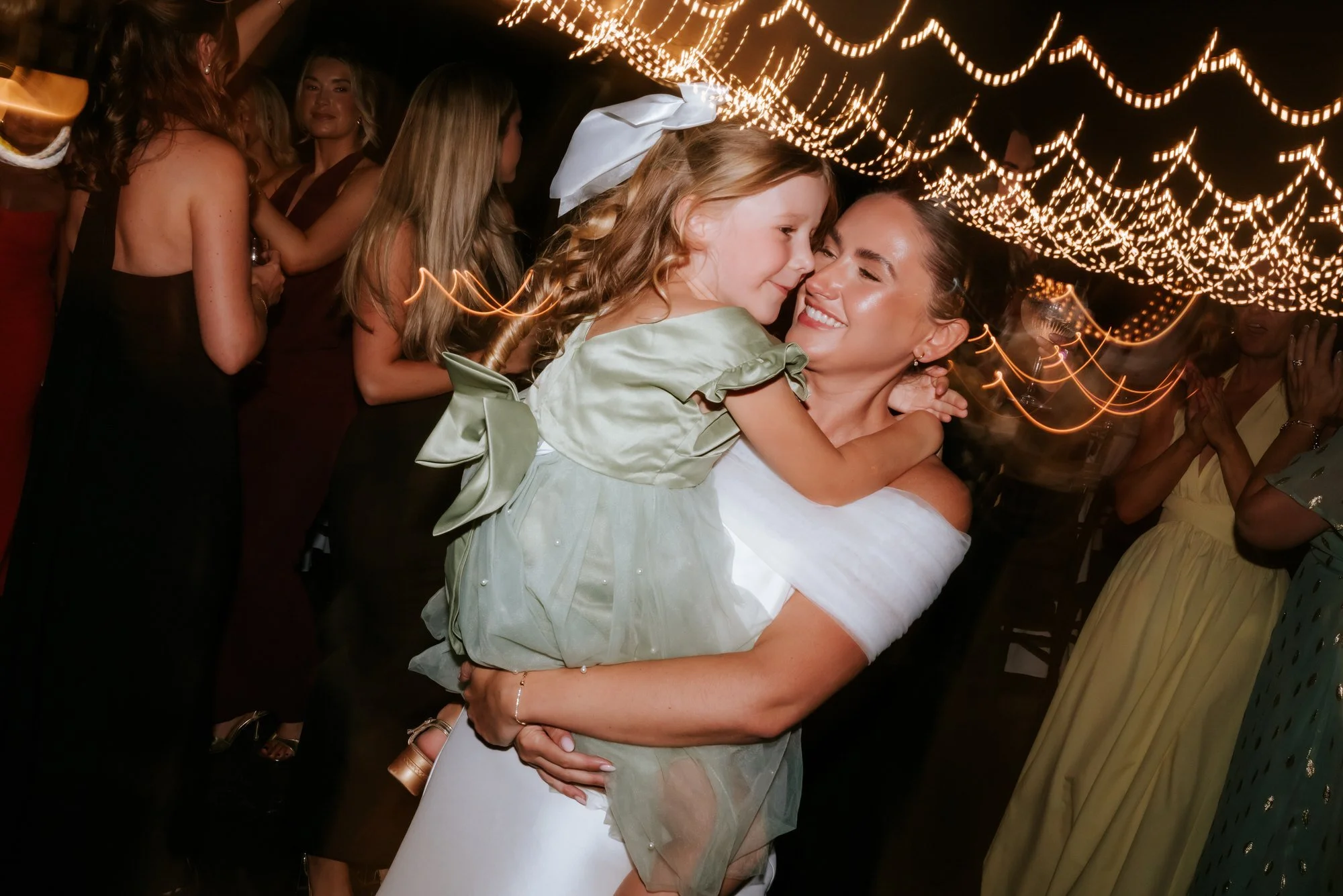 Caitlin holding a child and laughing on the dance floor.