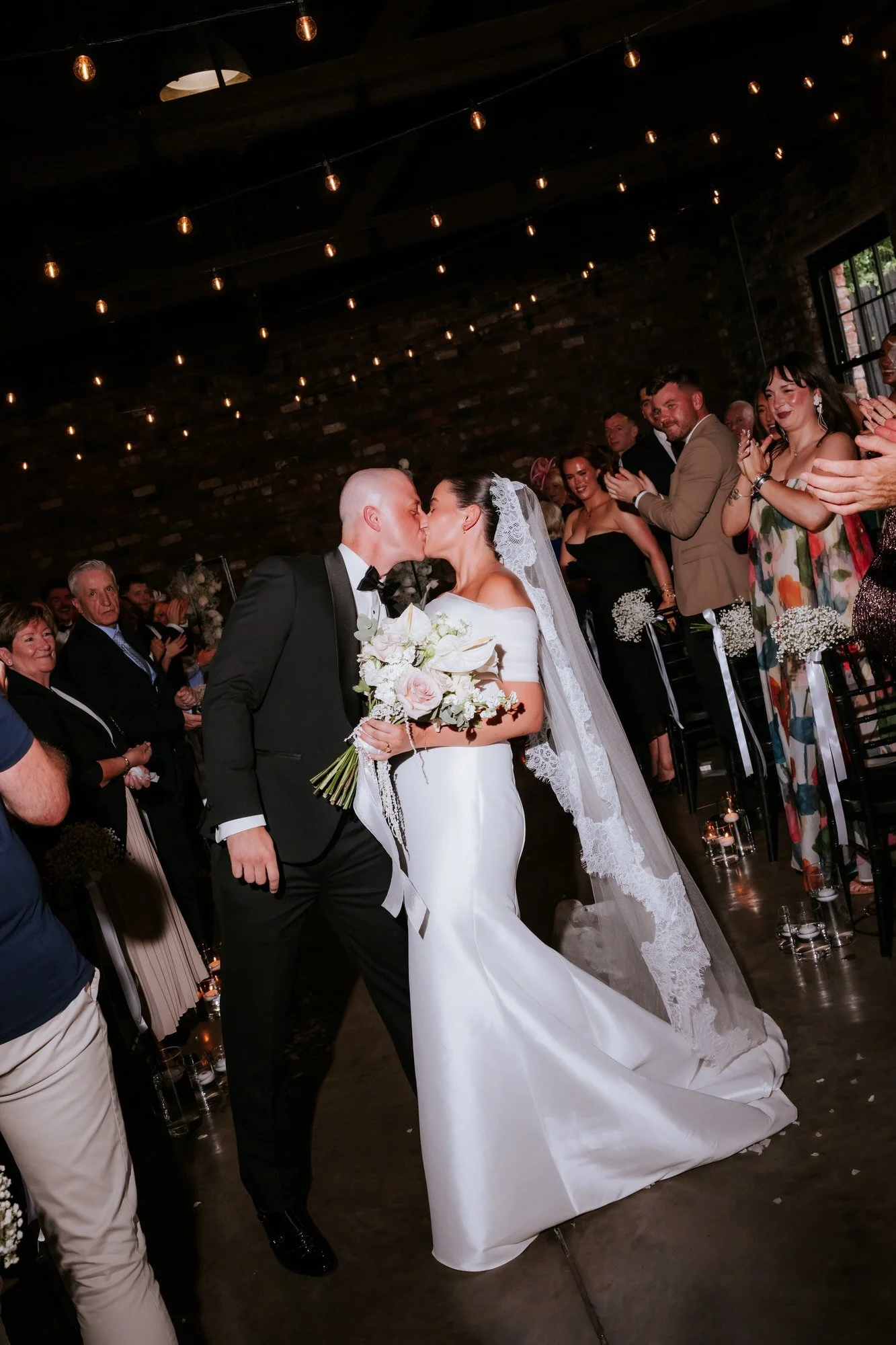Caitlin and Craig kissing as they walk back down the aisle.