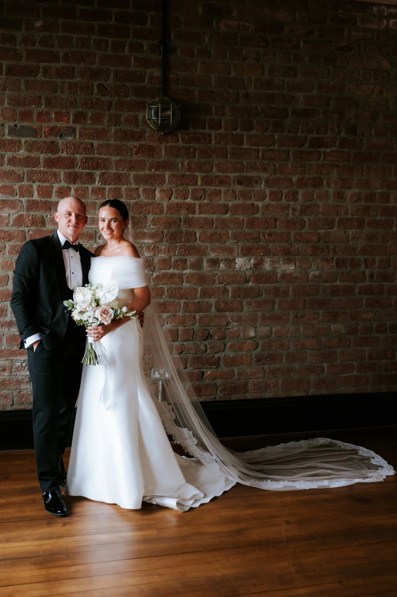 Caitlin and Craig together against the exposed brickwork inside The Engine Works.