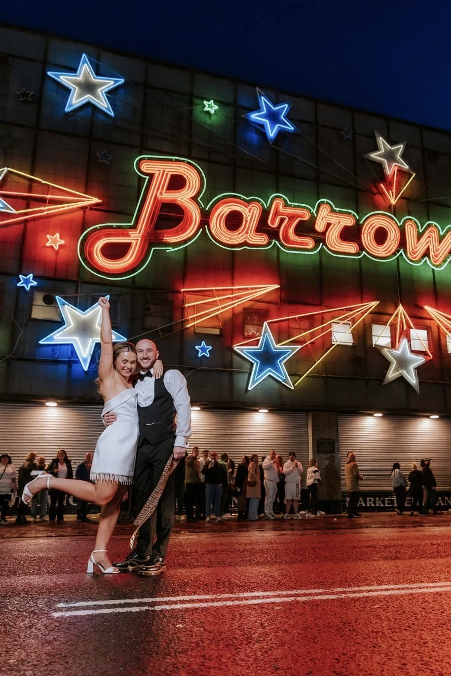 Rhona and Ciaran kissing beneath the glowing Barrowland sign.