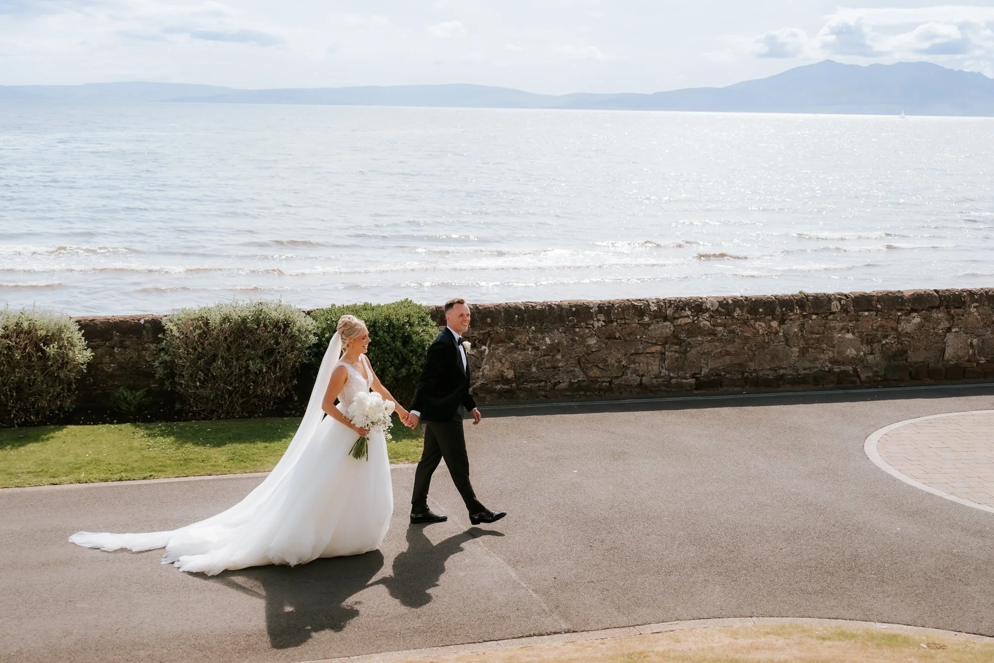 Nicole and Lawrence Shankland walking beside the sea at Seamill Hydro, with Arran across the water.