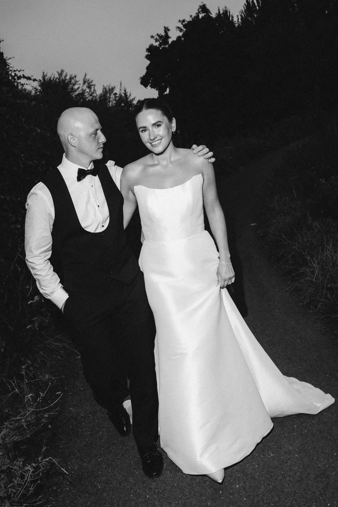 Craig looking towards Caitlin during their black and white evening portraits on the canal path.