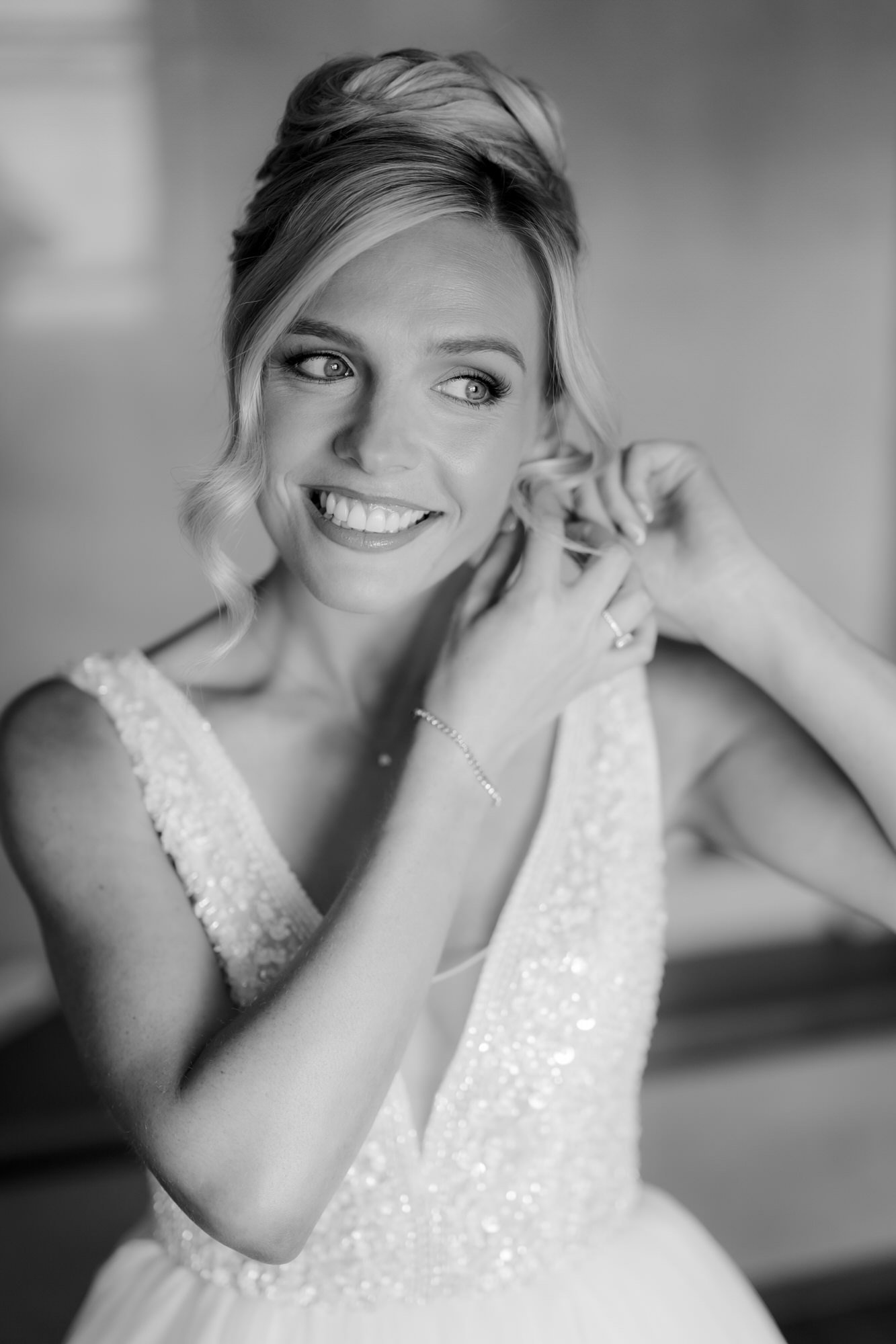 Black and white portrait of Nicole putting on her bridal earrings.