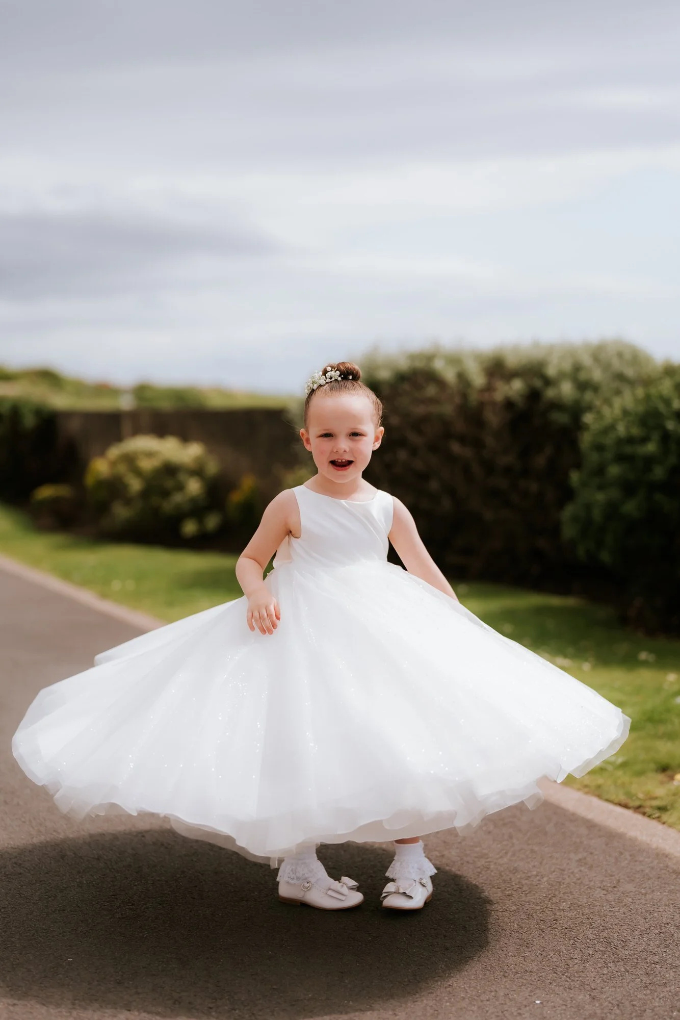 A flower girl twirling in her white dress.