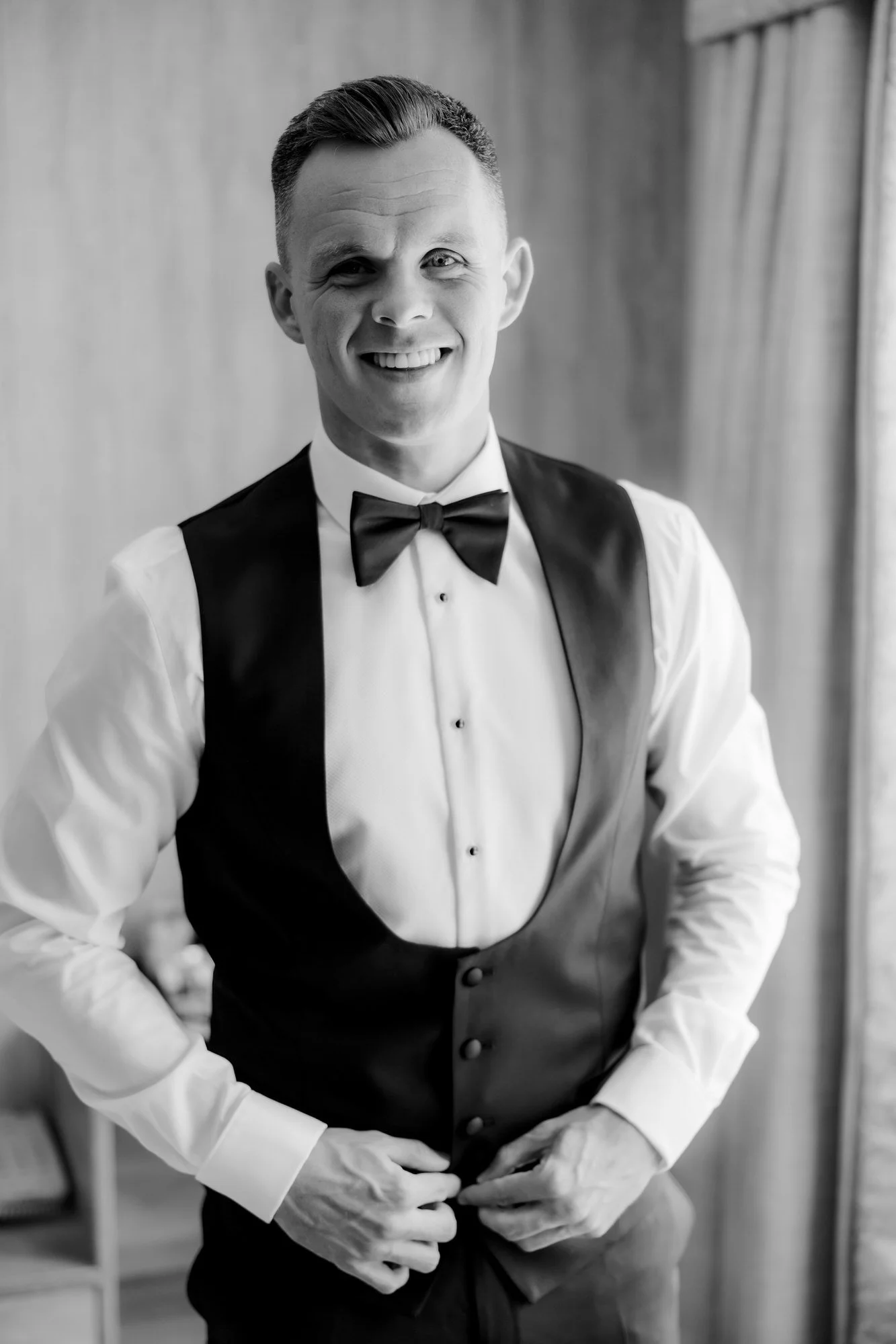 Lawrence Shankland getting ready in his wedding waistcoat, in black and white.