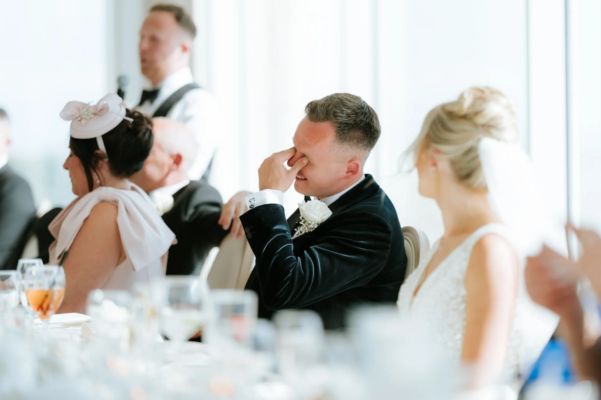 Lawrence laughing with his hand over his eyes during a speech.