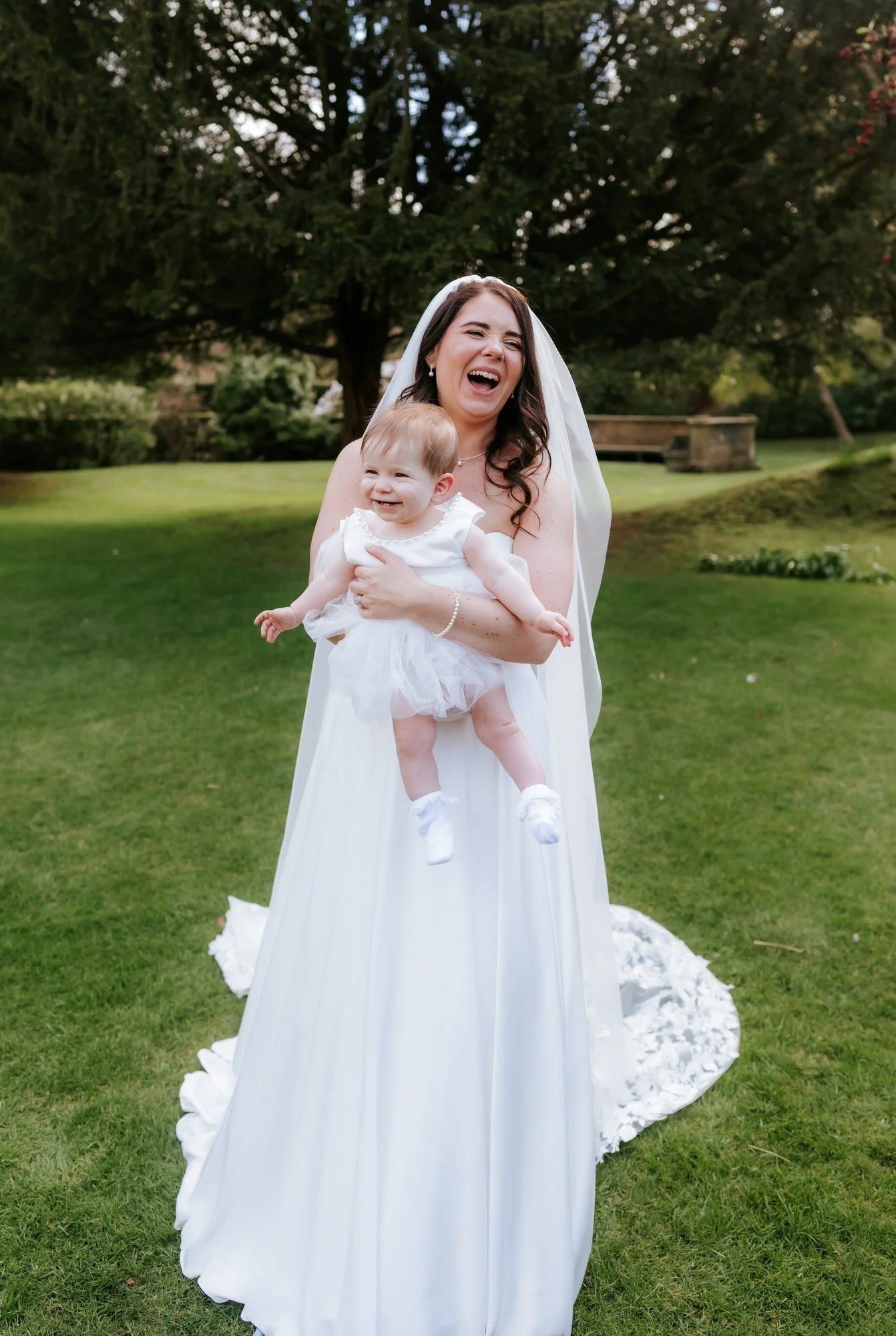 Steph laughing as she holds her baby outside Balbirnie House.