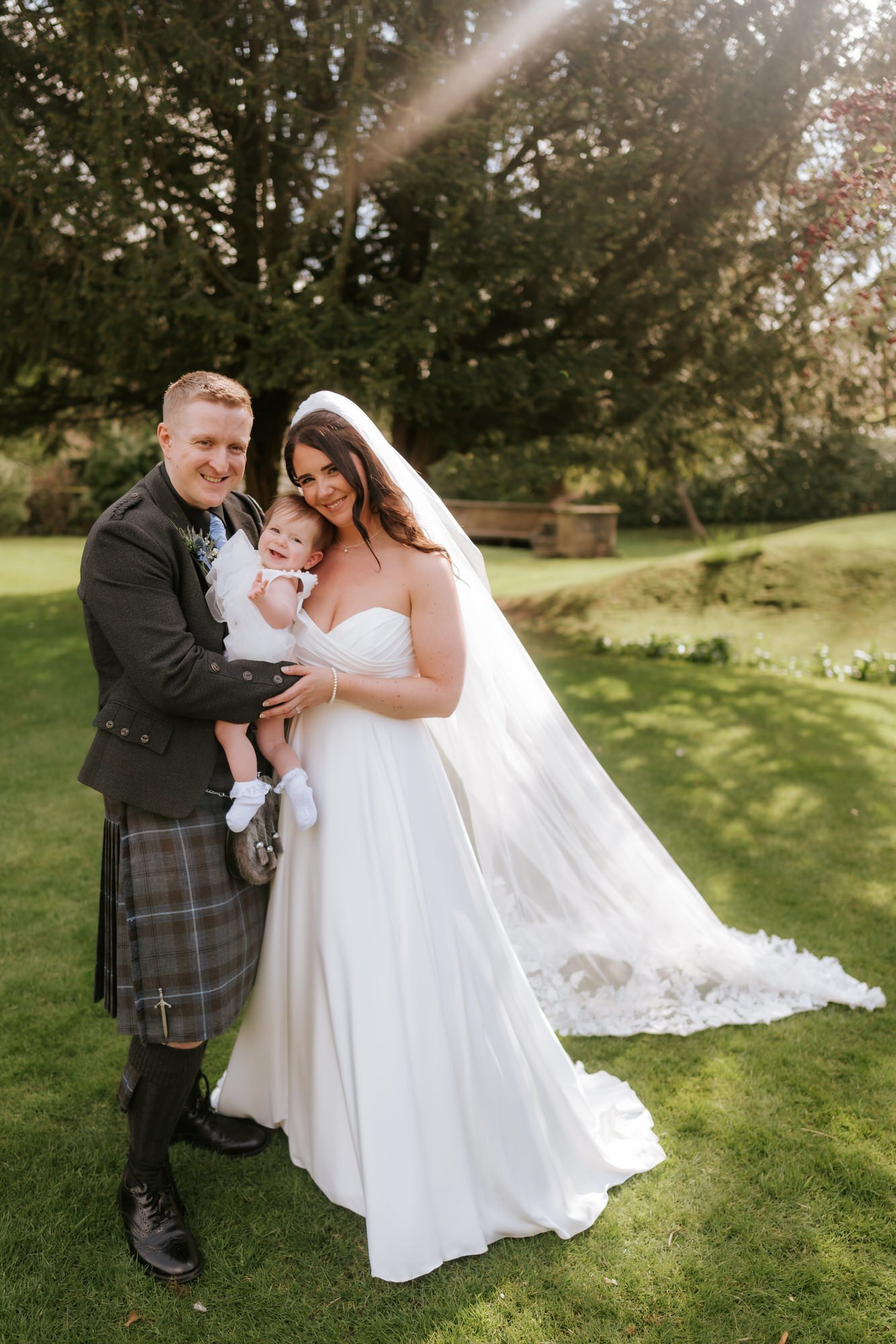 Steph and Calum enjoying a family portrait with their baby in the garden.