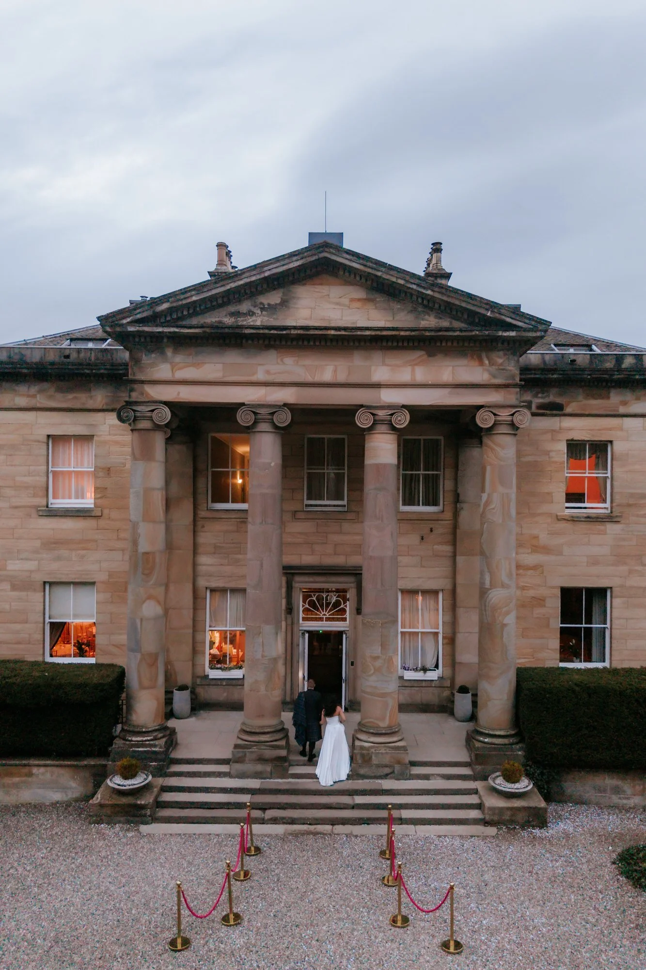 An aerial view of Steph and Calum on the front steps at Balbirnie House.