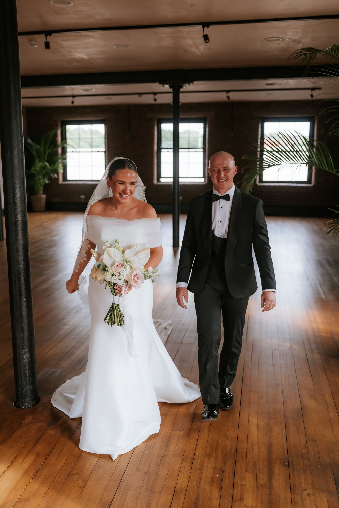 Caitlin and Craig laughing as they walk through the industrial wedding venue.