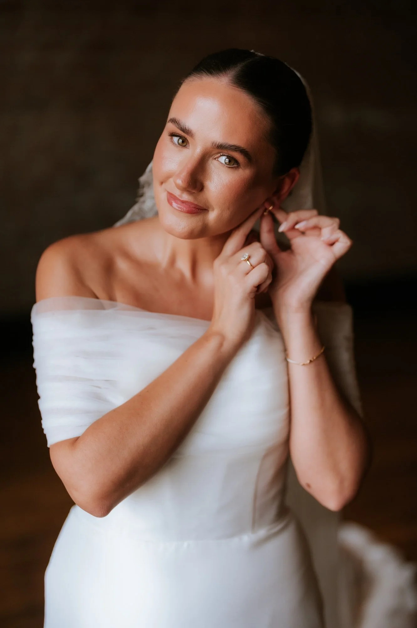 Caitlin smiling in her wedding dress and earrings before the ceremony.