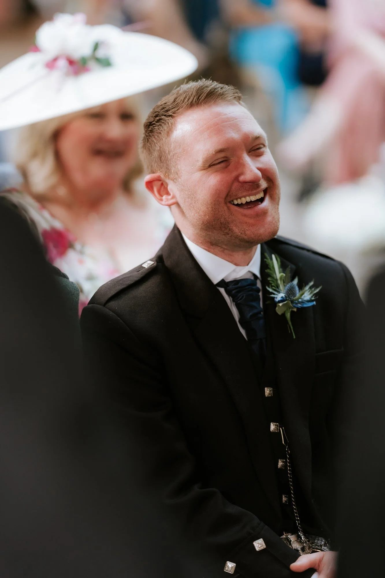A groomsman laughing during the wedding ceremony.
