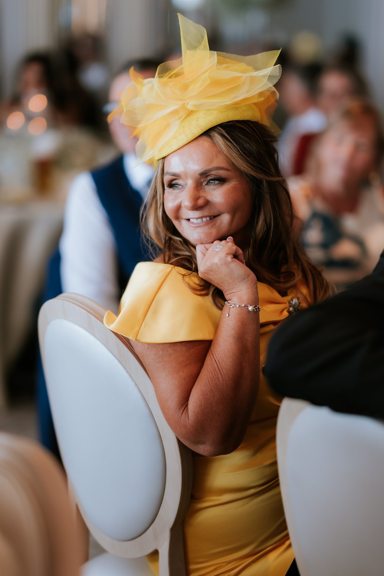 A guest in a yellow hat smiling at the wedding breakfast.