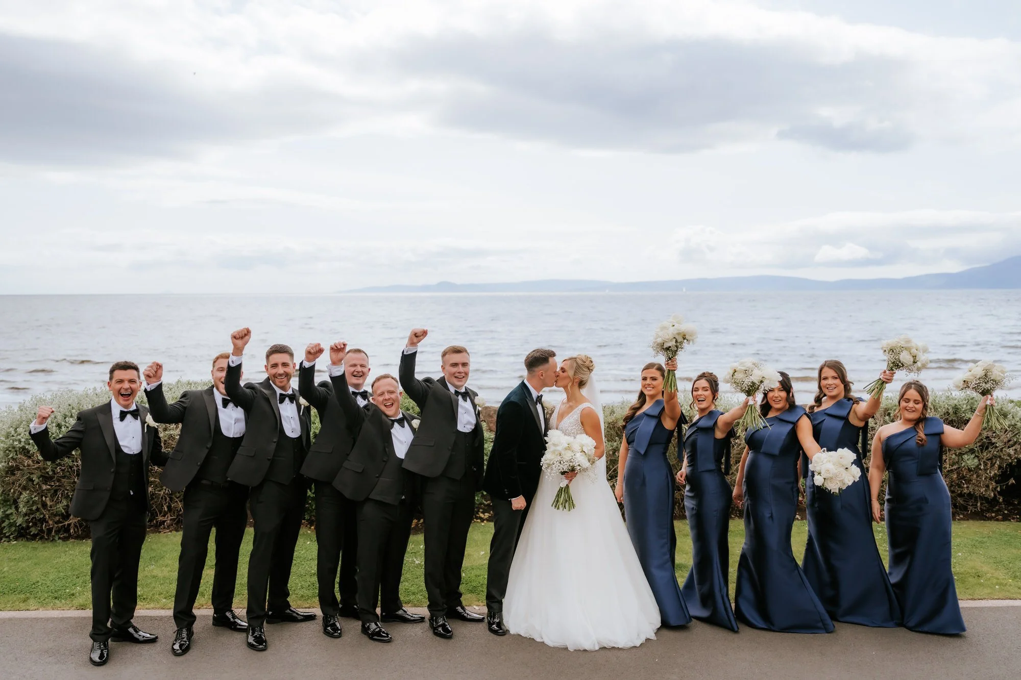 The wedding party cheering together beside the sea at Seamill.